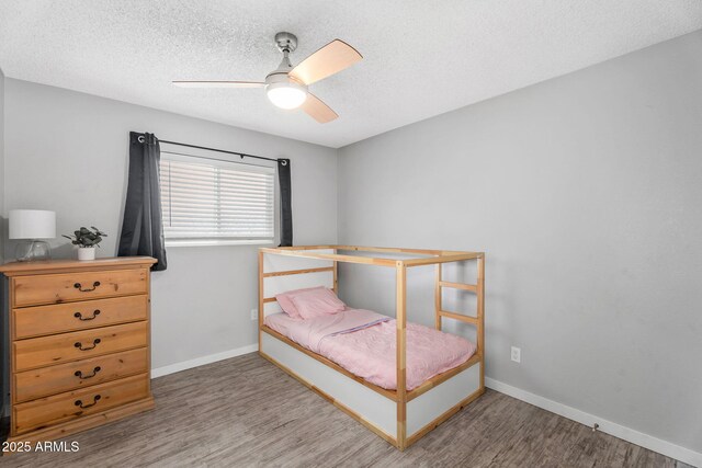 bedroom with baseboards, a ceiling fan, wood finished floors, and a textured ceiling