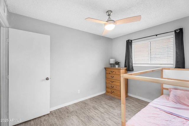 bedroom featuring baseboards, a ceiling fan, wood finished floors, and a textured ceiling