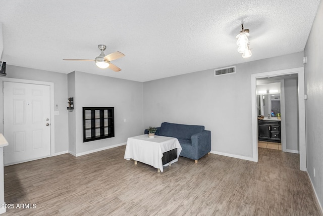 bedroom featuring wood finished floors, visible vents, a ceiling fan, baseboards, and a textured ceiling