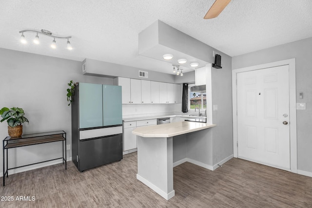 kitchen with a peninsula, appliances with stainless steel finishes, visible vents, and light wood-style flooring