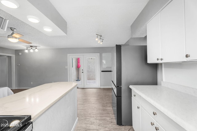 kitchen with light wood finished floors, stainless steel appliances, baseboards, a textured ceiling, and white cabinetry