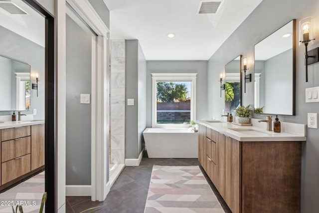 full bathroom with a soaking tub, double vanity, baseboards, and a sink