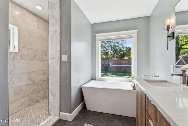 bathroom featuring baseboards, tiled shower, a freestanding tub, a sink, and tile patterned floors