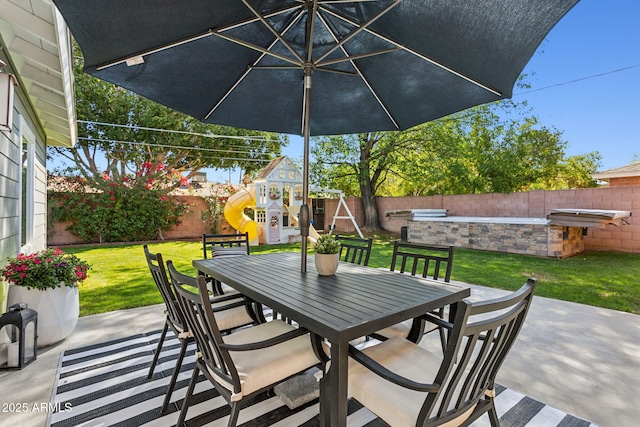 view of patio with outdoor dining space, a playground, and a fenced backyard