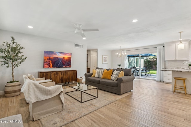 living area with recessed lighting, visible vents, light wood-style flooring, and ceiling fan with notable chandelier