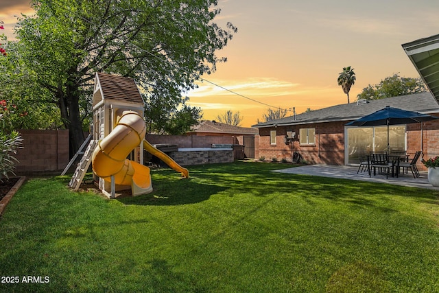 view of yard featuring a patio area, a fenced backyard, and a playground