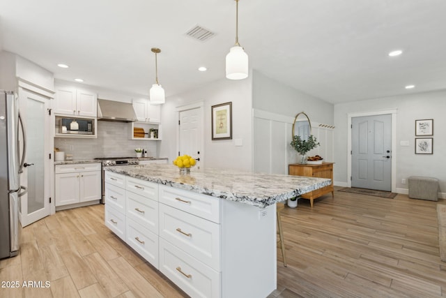 kitchen featuring visible vents, light wood-style flooring, backsplash, stainless steel appliances, and extractor fan