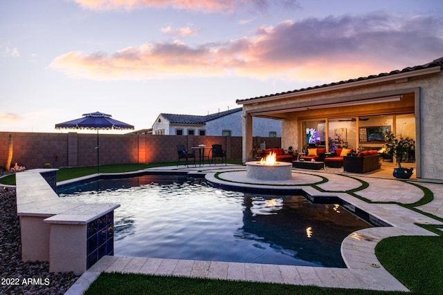 pool at dusk featuring a patio area and an outdoor living space with a fire pit