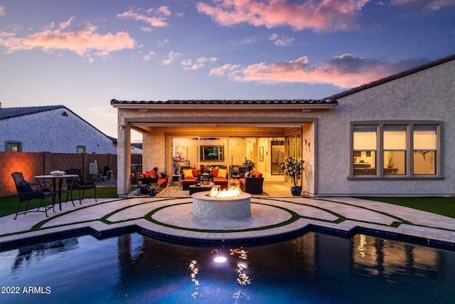 back house at dusk with a fenced in pool, a patio, and an outdoor fire pit