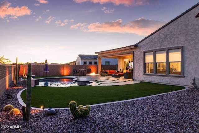 yard at dusk with an outdoor living space, a fenced in pool, and a patio