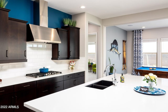 kitchen with stainless steel gas stovetop, tasteful backsplash, sink, dark brown cabinetry, and wall chimney exhaust hood