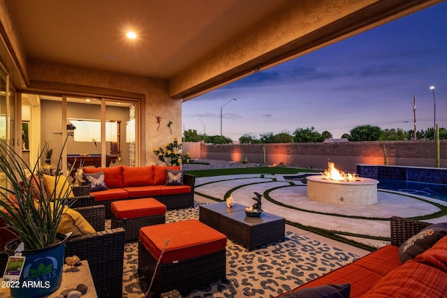 patio terrace at dusk with an outdoor living space with a fire pit