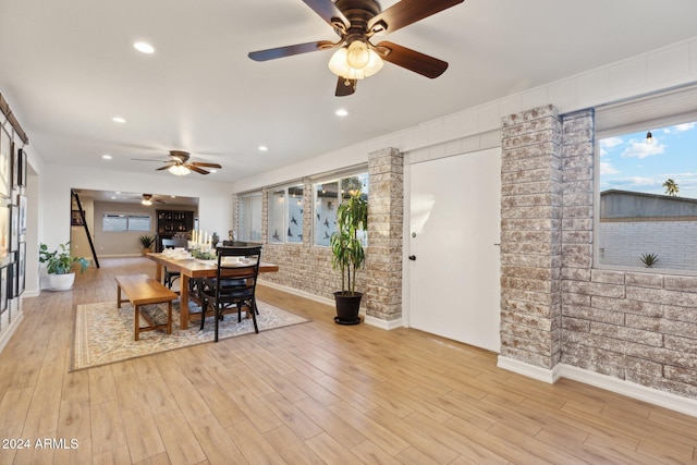 dining room with brick wall and light hardwood / wood-style floors