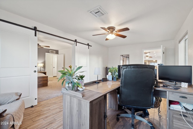 home office with ceiling fan and a barn door