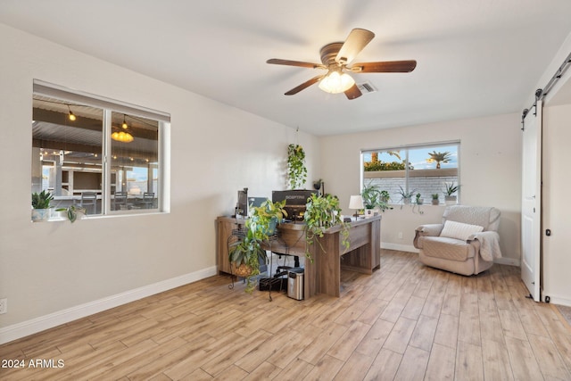 office space featuring ceiling fan, light hardwood / wood-style flooring, and a barn door