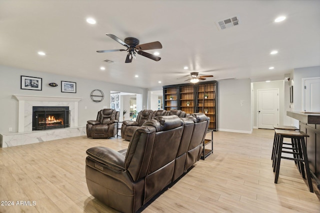 living room featuring ceiling fan, light wood-type flooring, and a high end fireplace