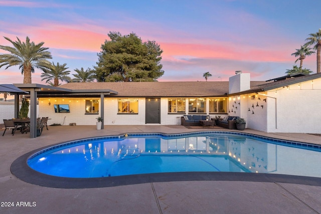 pool at dusk featuring a patio area and outdoor lounge area