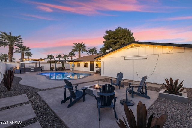 pool at dusk featuring a patio area and an outdoor fire pit