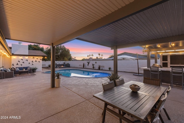 pool at dusk with an outdoor living space, an outdoor bar, and a patio area