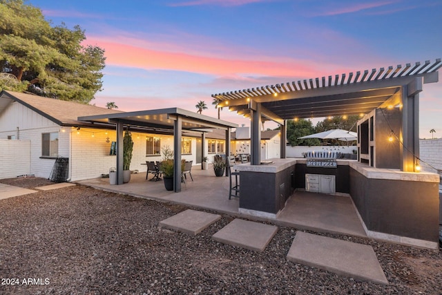 patio terrace at dusk with a pergola and area for grilling