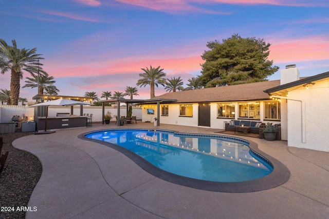 pool at dusk featuring an outdoor hangout area and a patio area