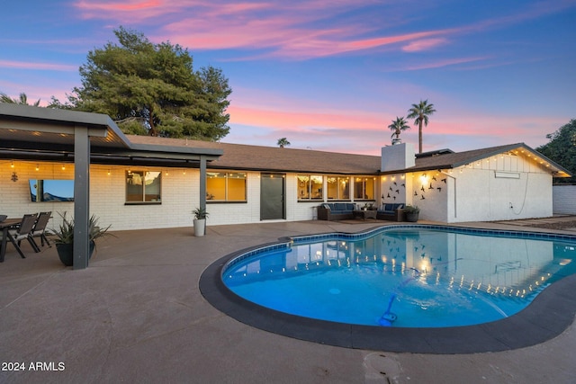 pool at dusk with a patio area