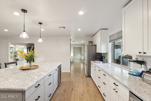 kitchen featuring a kitchen island, white cabinetry, hanging light fixtures, light wood-type flooring, and light stone counters