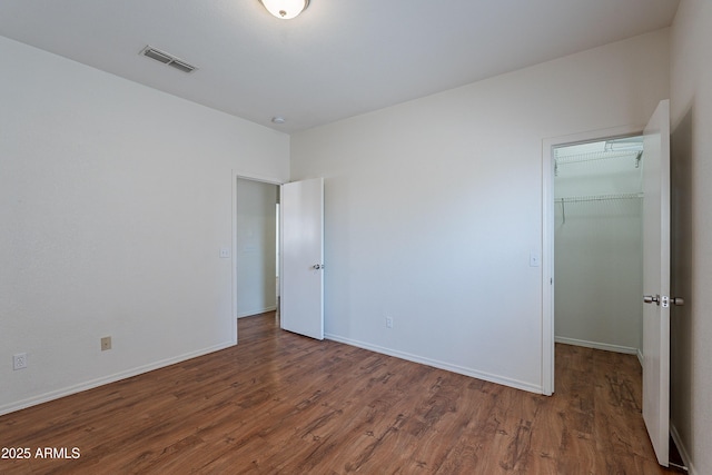 14244 N 132nd Ln, Surprise, AZ 85379 - unfurnished bedroom featuring a closet, wood finished floors, visible vents, a walk in closet, and baseboards