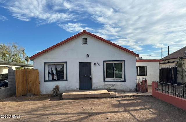 view of front of house featuring a tile roof, fence, a gate, and stucco siding