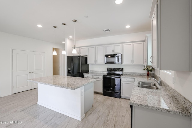 kitchen with light stone counters, sink, black appliances, decorative light fixtures, and a kitchen island