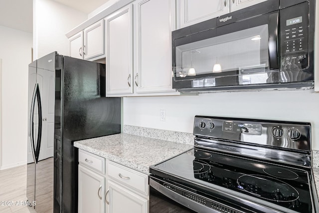 kitchen featuring light stone countertops, white cabinets, and black appliances