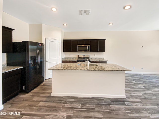 kitchen featuring appliances with stainless steel finishes, light stone countertops, and an island with sink