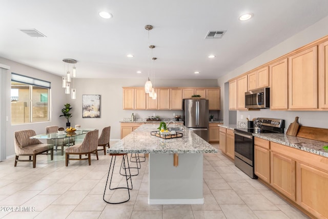 kitchen with light brown cabinetry, appliances with stainless steel finishes, a kitchen island, and visible vents