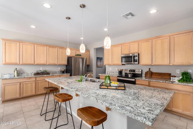 kitchen featuring a center island with sink, a breakfast bar area, visible vents, appliances with stainless steel finishes, and light brown cabinets