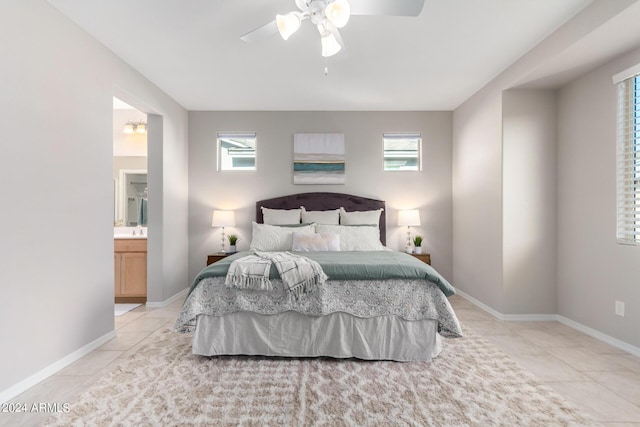 bedroom with light tile patterned floors, baseboards, a ceiling fan, and ensuite bathroom