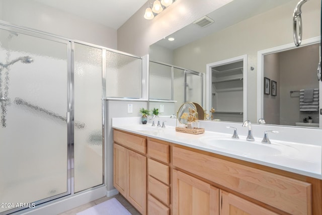 full bathroom featuring double vanity, a stall shower, visible vents, and a sink