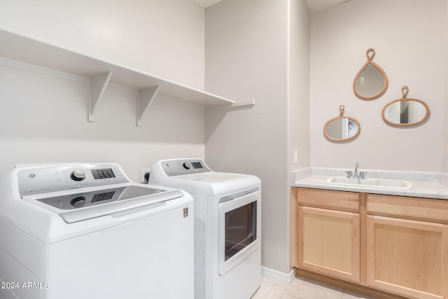 laundry room featuring light tile patterned floors, cabinet space, washer and dryer, and a sink