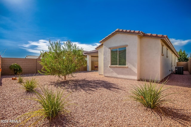 rear view of house with cooling unit, a fenced backyard, a tile roof, and stucco siding