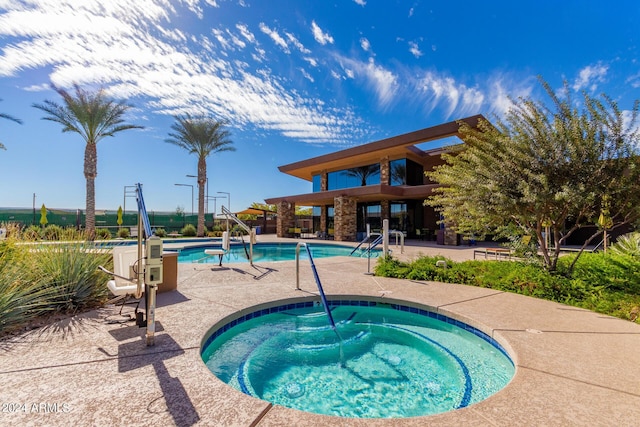 pool with a hot tub and a patio