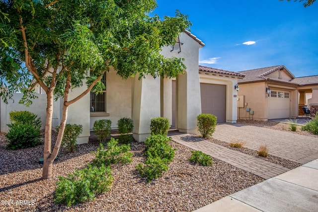 view of front of property with an attached garage, a tile roof, decorative driveway, and stucco siding