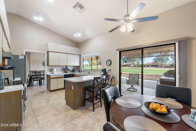 kitchen with white cabinetry, ceiling fan, high vaulted ceiling, a breakfast bar, and light tile patterned floors