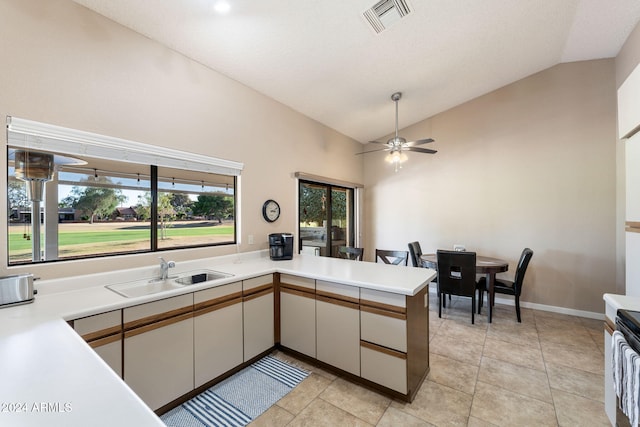 kitchen featuring kitchen peninsula, ceiling fan, sink, white cabinetry, and lofted ceiling