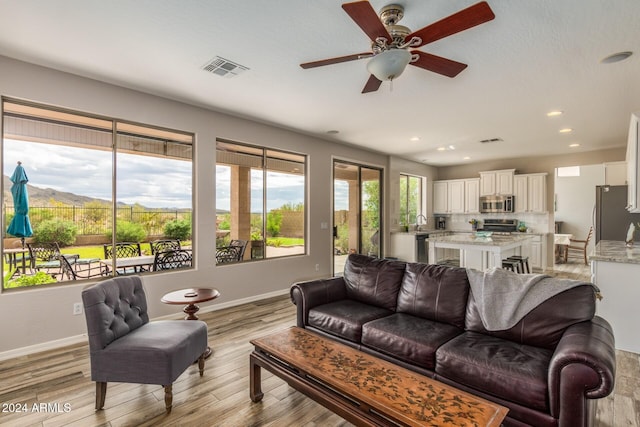 living room with light wood-type flooring and ceiling fan