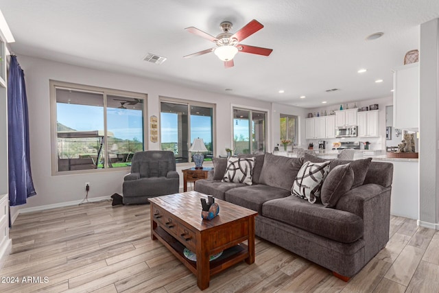 living room with ceiling fan and light wood-type flooring