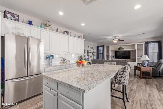 kitchen with light hardwood / wood-style floors, white cabinetry, and stainless steel refrigerator