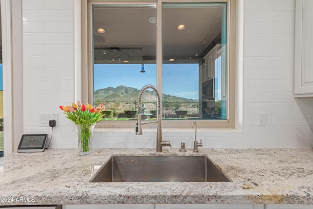 interior details featuring tasteful backsplash, a mountain view, sink, and light stone counters