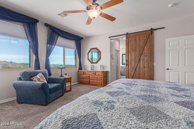 bedroom with a barn door, light colored carpet, and ceiling fan