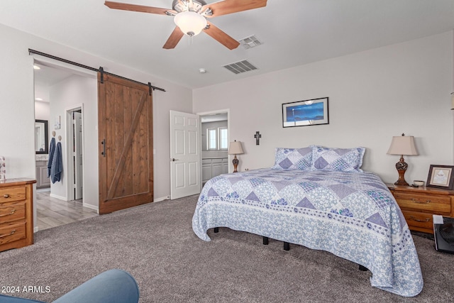 bedroom featuring ceiling fan, a barn door, and light colored carpet