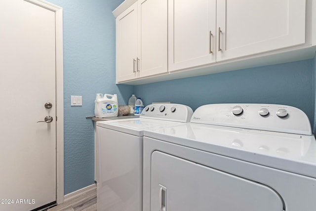 laundry area with washer and dryer, light hardwood / wood-style floors, and cabinets