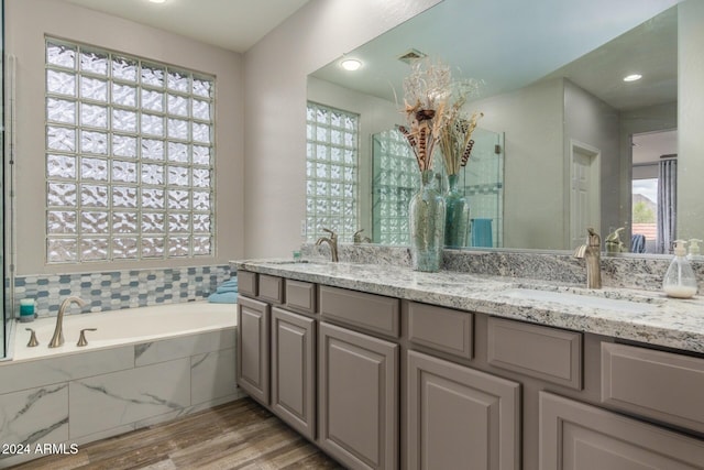 bathroom featuring tiled bath, vanity, and hardwood / wood-style flooring